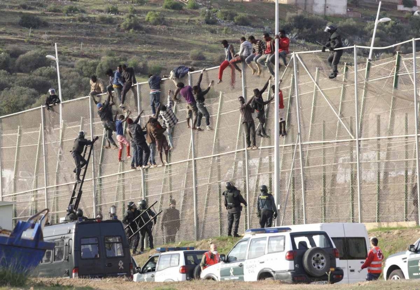 Inmigrantes y guardias civiles en la valla de Melilla Inmigrantes y guardias civiles en la valla de Melilla