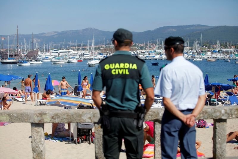 Un guardia civil y un agente local vigilan una playa.
