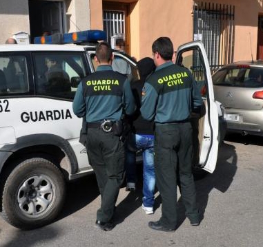 Dos guardias civiles introducen a un detenido en un vehículo oficial Dos guardias civiles introducen a un detenido en un vehículo oficial